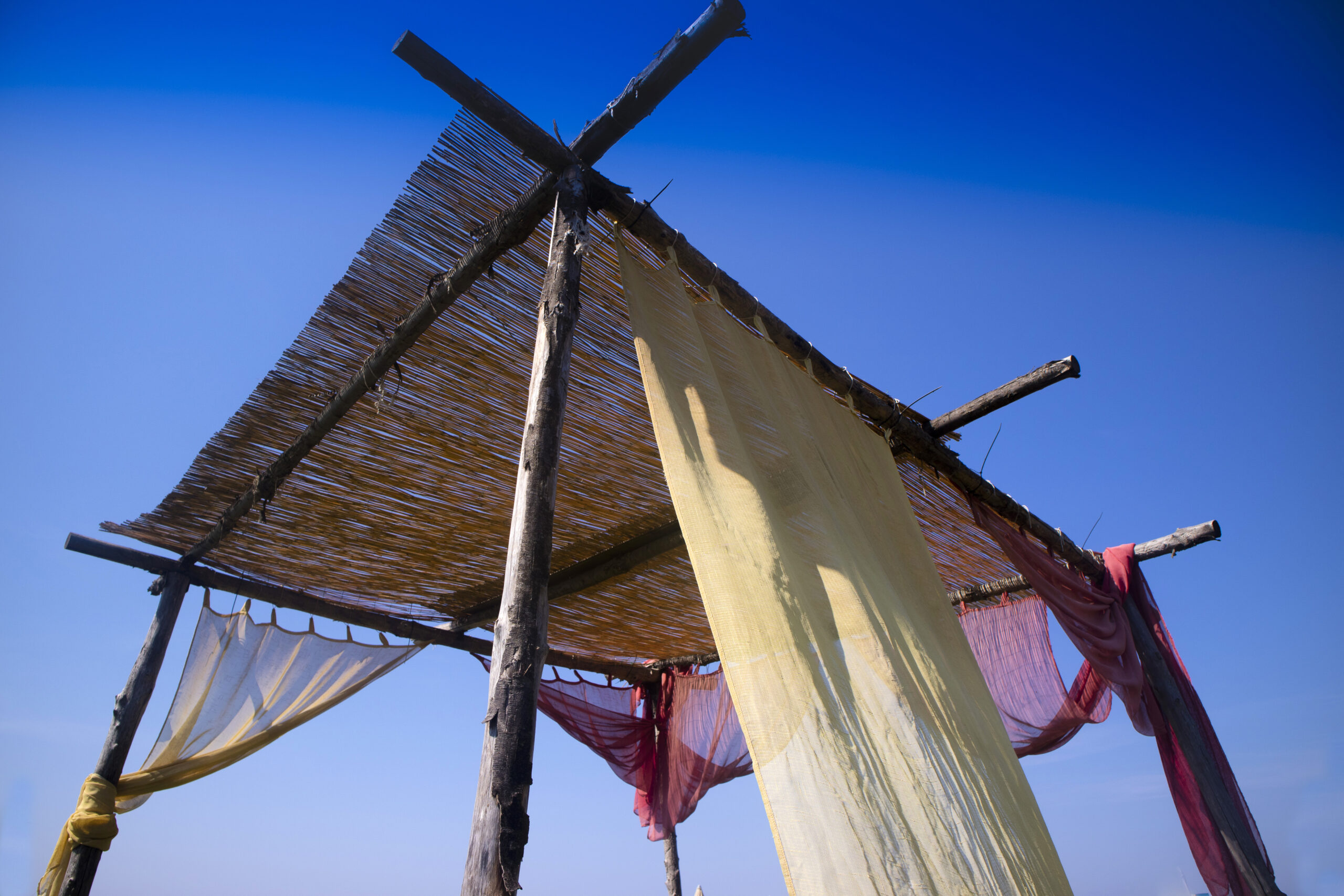 Small summer gazebo built with wooden poles and canes